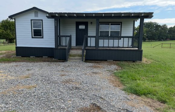 Charming, single-story house with a covered front porch, gravel driveway, and open grassy yard under a partly cloudy sky—ideal for home renovations in North Texas.